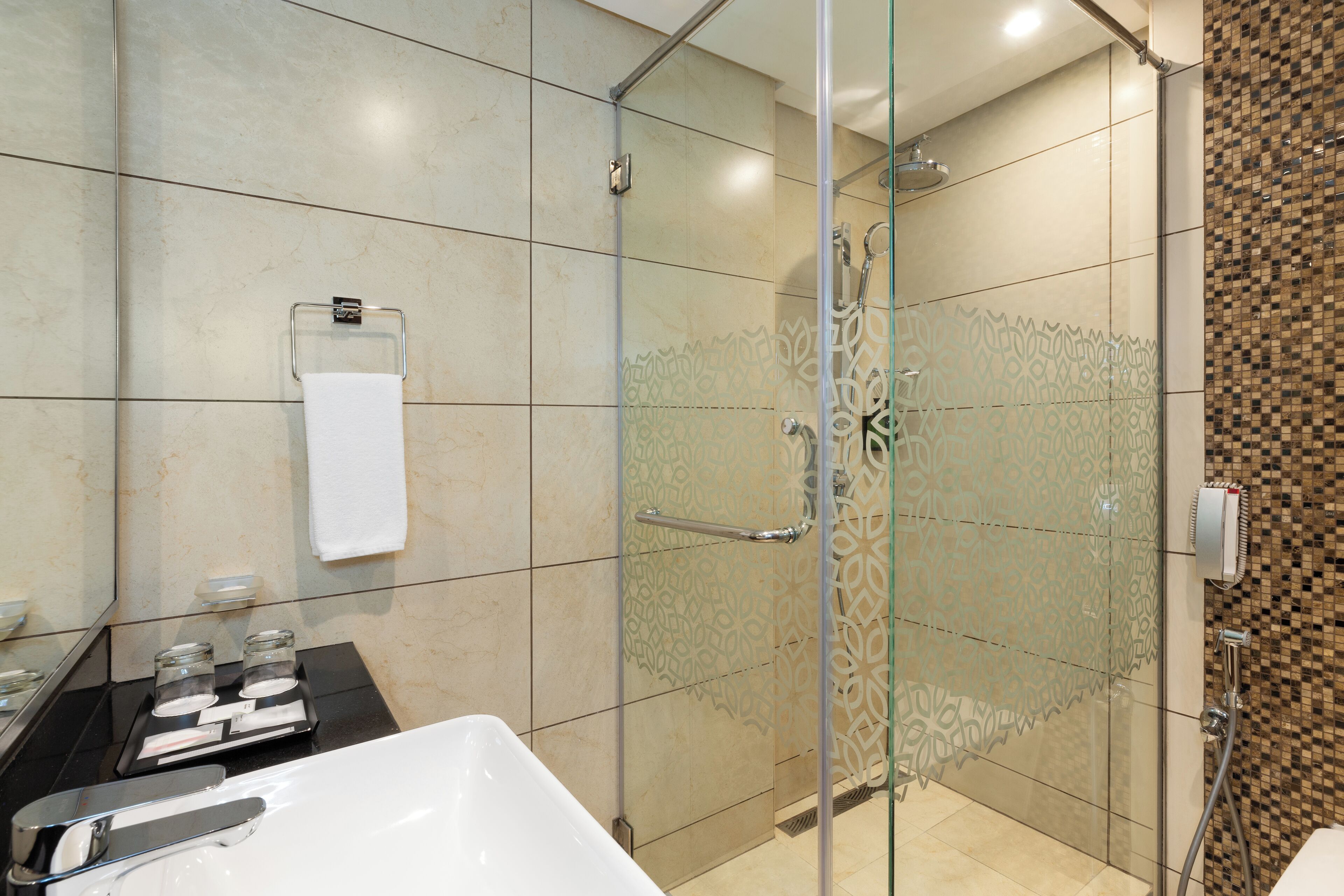 Un baño moderno con ducha envuelta en vidrio, bañera blanca y piso de baldosas.