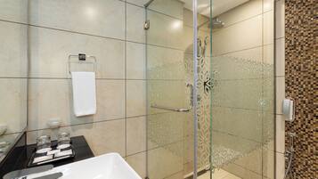 Un baño moderno con ducha envuelta en vidrio, bañera blanca y piso de baldosas.