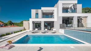 A modern two-story house with a swimming pool, outdoor seating, and a stone wall. - Beach front home in Medulin (Medulin)