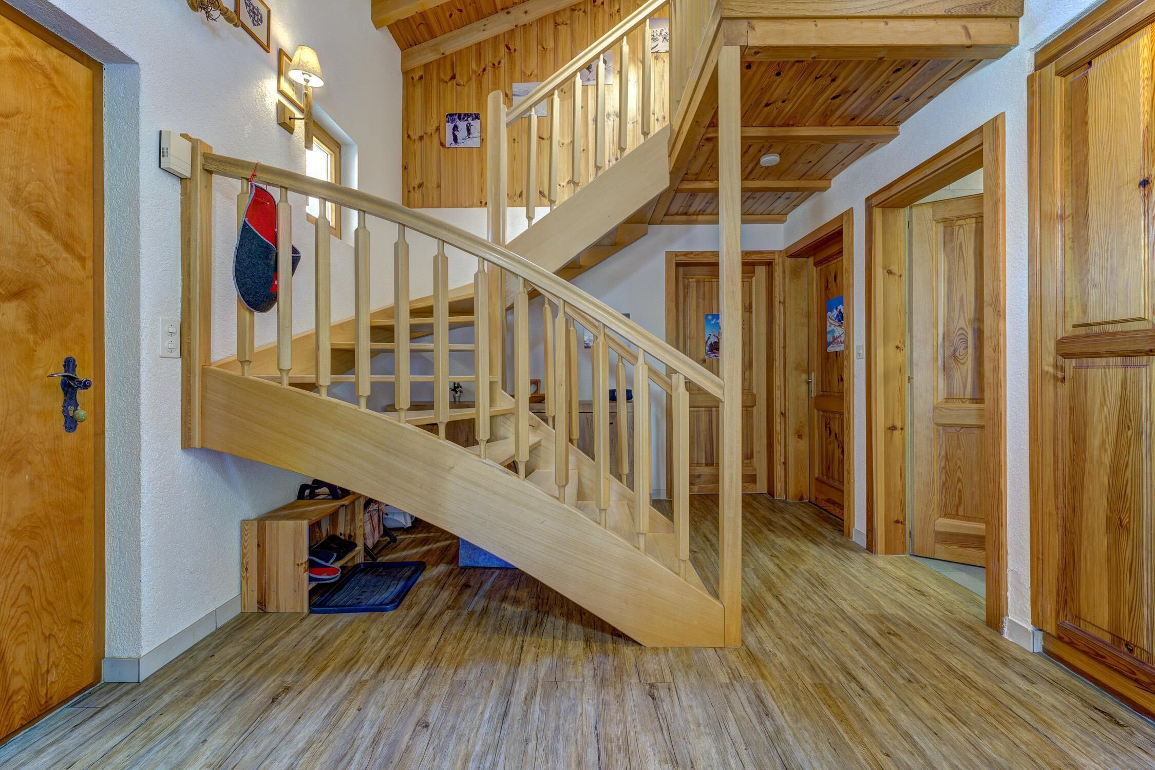A wooden staircase leading to an upper level, with a door on the left and a door on the right.