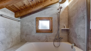 A modern bathroom with a freestanding bathtub, a showerhead, and a small window above the door. - Chalet Khione - La Tzoumaz, 4 Vallees (La Tzoumaz)