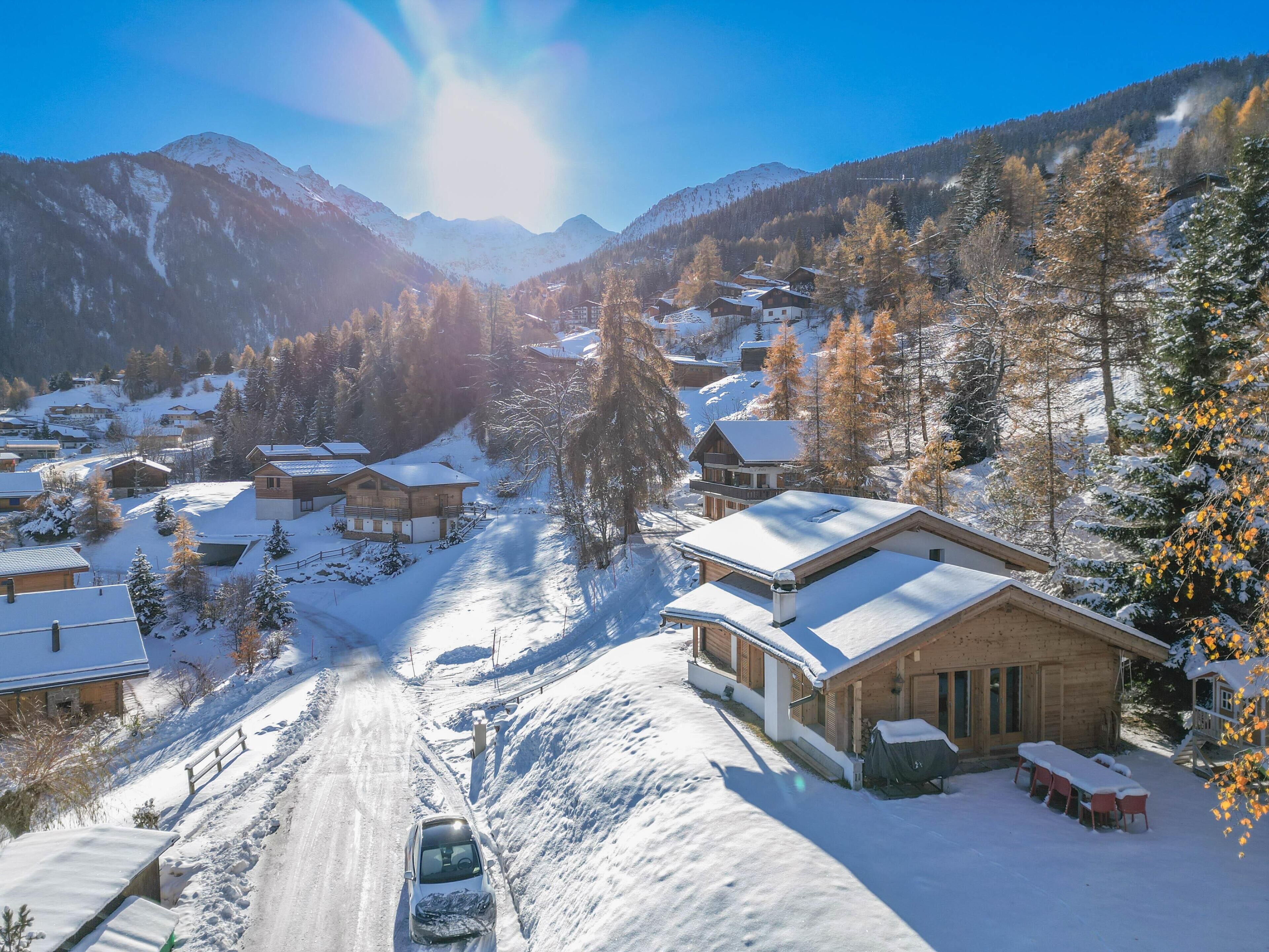 A snow-covered mountain village with wooden houses and a clear sky.