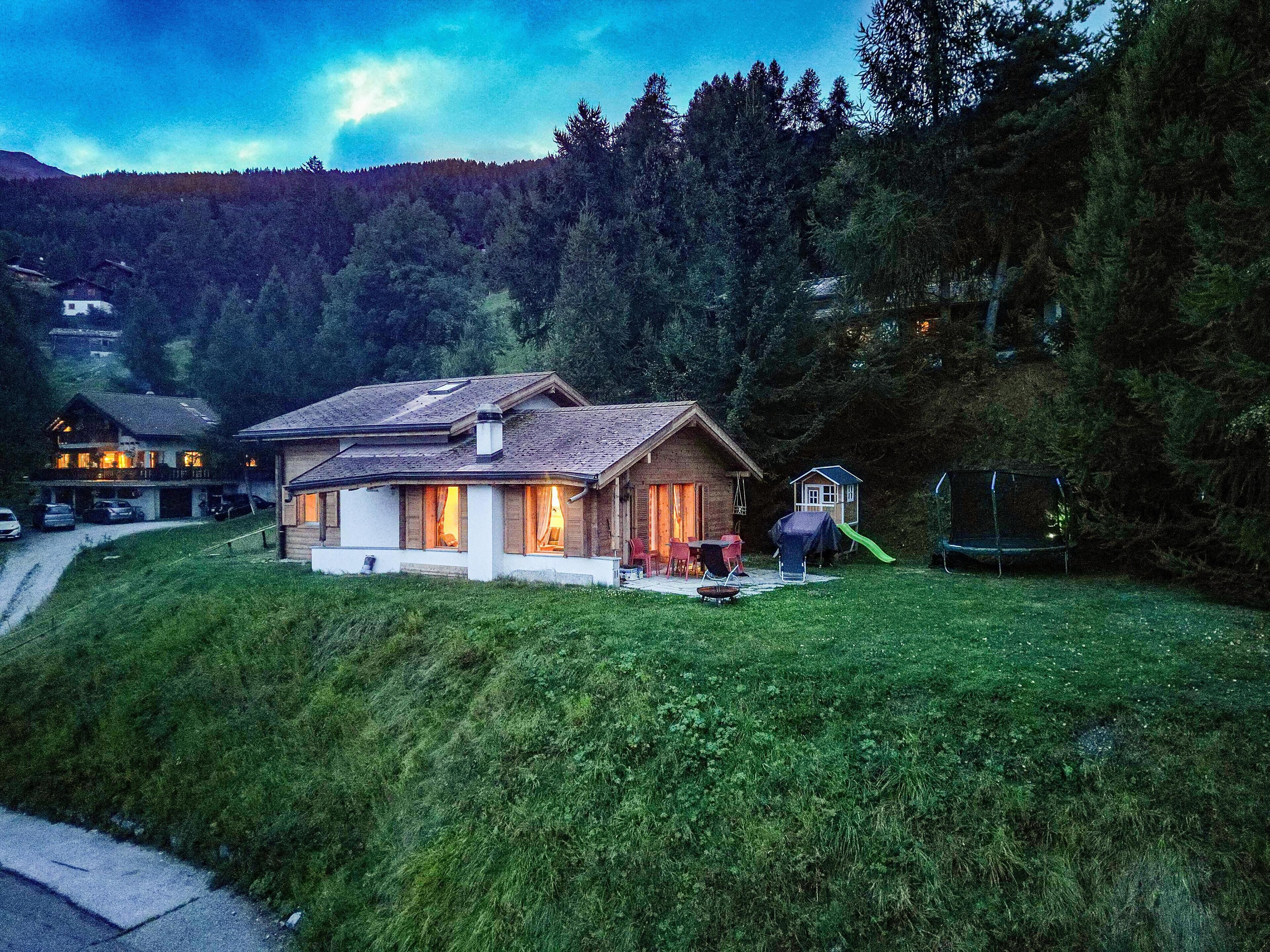 A two-story house with a sloped roof, a small deck, and a slide in the backyard.