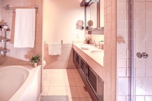 Une salle de bain moderne avec une baignoire, un lavabo avec un miroir et un espace douche.