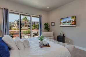 A spacious bedroom with a large bed, a view of a pool and outdoor seating area, and a framed picture on the wall.
