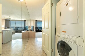 Un lavadero con lavadora de carga frontal, una kitchenette pequeña y vistas al balcón.