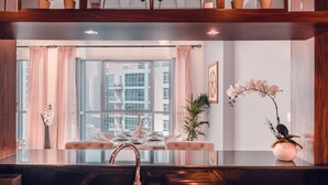 Una cucina moderna con un tavolo da pranzo in vetro, tende rosa e piante in vaso.
