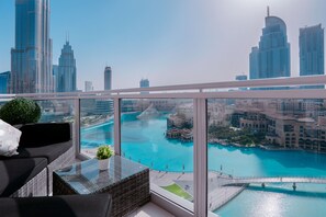 A balcony with a view of a city skyline and a turquoise body of water.