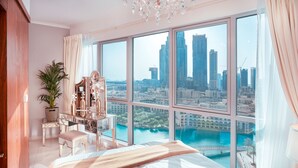 A bedroom with a large window, a bed, a vanity with a mirror, and a potted plant. - Elite Royal Apartment | Burj Khalifa & Fountain view | Star (Dubai)