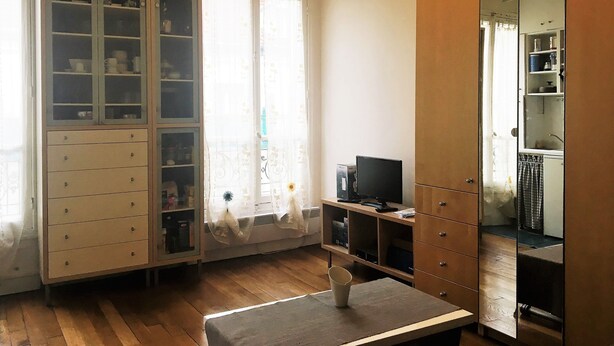 A room with a wooden floor, a large mirror, a television, and a cabinet with multiple drawers. - Monceau (Claude Pouillet) ID 302 (Paris)