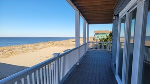 Una terraza de madera con barandal blanco que da a una playa.