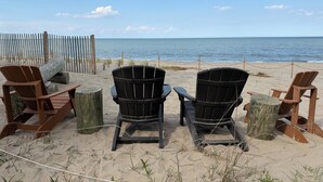 Vista de playa con sillas de madera y una valla.
