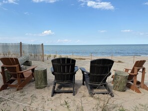 Vista sulla spiaggia con sedie e recinzione in legno.