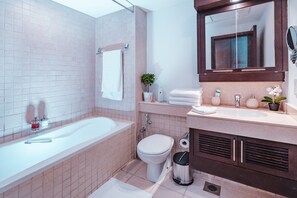 A modern bathroom with a bathtub, toilet, sink, and a large mirror.