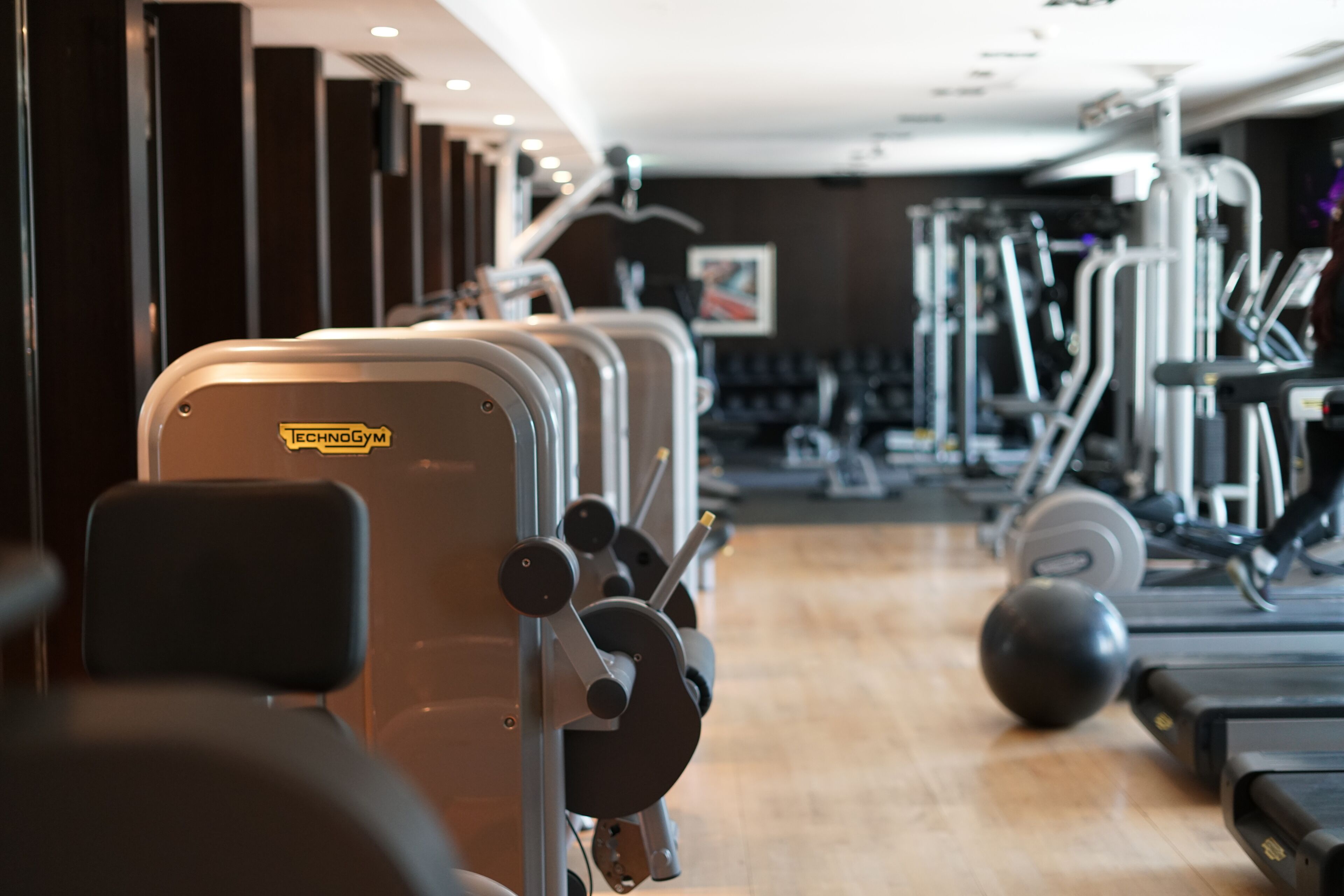 Uma academia com aparelhos de cardio, equipamentos de musculação e esteira.
