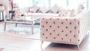 Ein modernes Wohnzimmer mit einer gepolsterten Couch, einem Glastisch und einer dekorativen Vase.