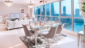 A spacious living room with a large glass table, elegant chairs, a plush sofa, and a city view. - Elite Royal Apartment - Burj Khalifa & Fountain view - The Royal (Dubai)