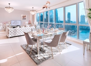 Relax in style with a plush sofa, glass dining table, and stunning city views through floor-to-ceiling windows.