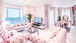 Een ruime woonkamer met een grote bank, een salontafel en een televisie. Er is een eethoek met een tafel en stoelen.