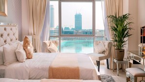 Ruime slaapkamer met een groot bed, een zithoek en uitzicht op een stadsgezicht en een waterpartij.