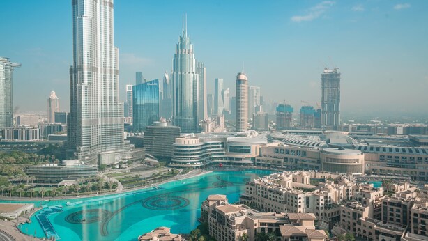 A cityscape with modern skyscrapers, a central water feature, and surrounding traditional architecture.