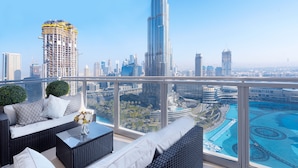 A high-rise balcony with a city view, including a tall building under construction, a swimming pool, and outdoor furniture.