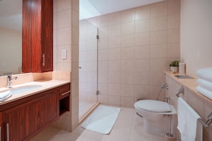 A modern bathroom with a wooden vanity, a shower, and a toilet.