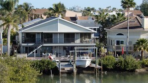 Une grande maison à deux étages avec un balcon, une jetée et un bateau.