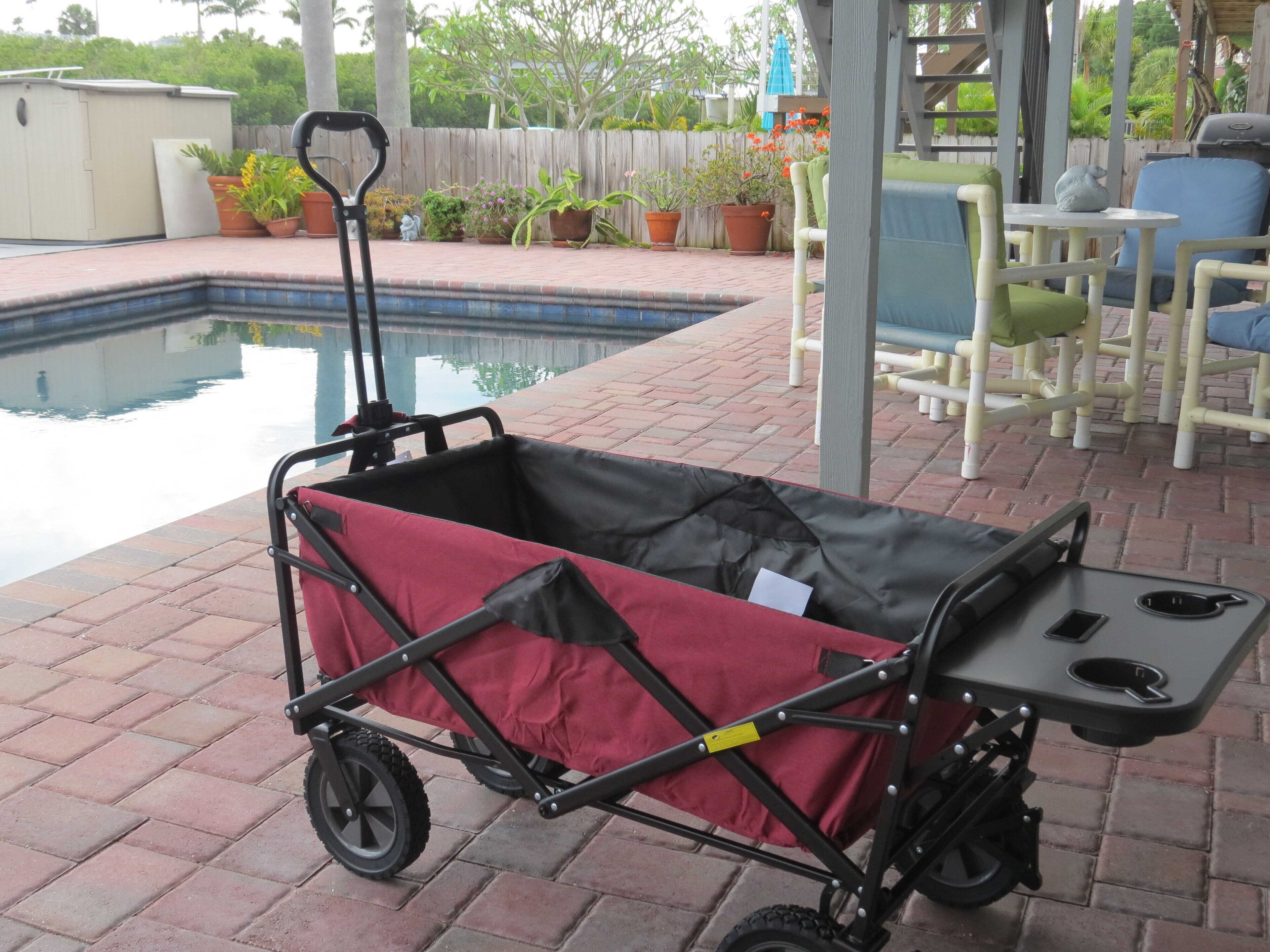Un patio couvert avec une piscine, un chariot pliable et du mobilier d’extérieur.