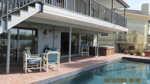 Un espace aménagé au bord de la piscine, avec des chaises longues, un jacuzzi et une terrasse couverte.