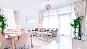 Ein modernes Wohnzimmer mit Essbereich, großen Fenstern und einer Deckenleuchte.