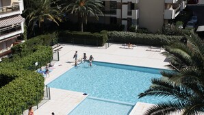 A swimming pool surrounded by greenery and buildings. - COMFORTABLE 4/5-ROOM APARTMENT IN SECURE RESIDENCE WITH SWIMMING POOL (Saint-Raphaël)
