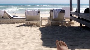 Een uitzicht op het strand met ligbedden en een rieten constructie.