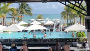 Een poolbar met uitzicht op een zwembad en palmbomen.