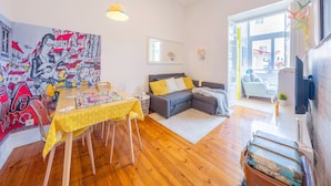 A cozy living room with a dining area, a gray sofa, and a colorful mural on the wall. - Family Dream | A/C | Balcony & View | Lofts | Desk (Lisboa)