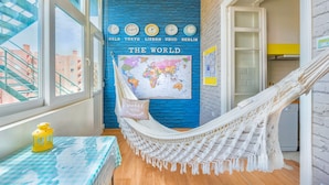 A room with a hammock, a world map, clocks showing different cities, and a view of buildings outside. - Family Dream | A/C | Balcony & View | Lofts | Desk (Lisboa)