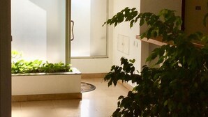 Un intérieur moderne avec une porte vitrée donnant sur un balcon, une plante en pot et un sol carrelé.
