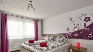Ein Schlafzimmer mit einem Bett, einem Nachttisch, einem Sessel und einer Wand mit floralem Dekor.