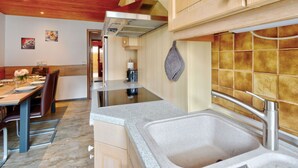 Eine moderne Küche mit Granitarbeitsplatten, einer Edelstahlspüle, Holzschränken und einer roten Decke.
