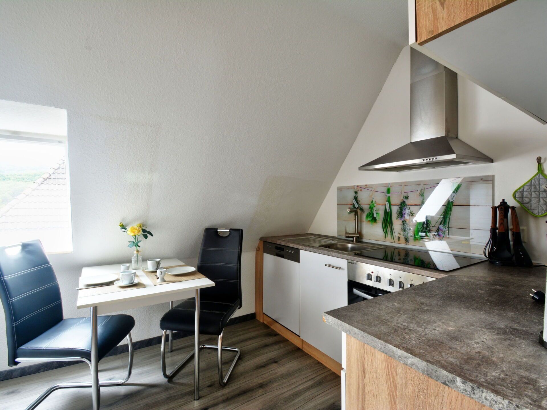 Een compacte keuken met een zithoek, een ingebouwde kookplaat en een raam voor natuurlijk licht.
