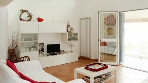 A modern living room with white furniture, a television, and a bookshelf. - Beautiful  villa for 9 people with WIFI, A/C, TV, terrace and pets allowed (Sanremo)