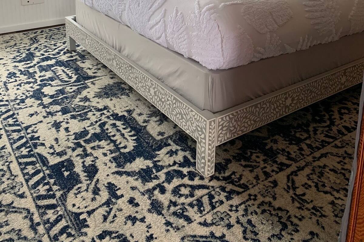Ein Schlafzimmer mit einem großen Bett, einer Sterndekoration, einem gemusterten Teppich und Blick auf Boote vor dem Fenster.
