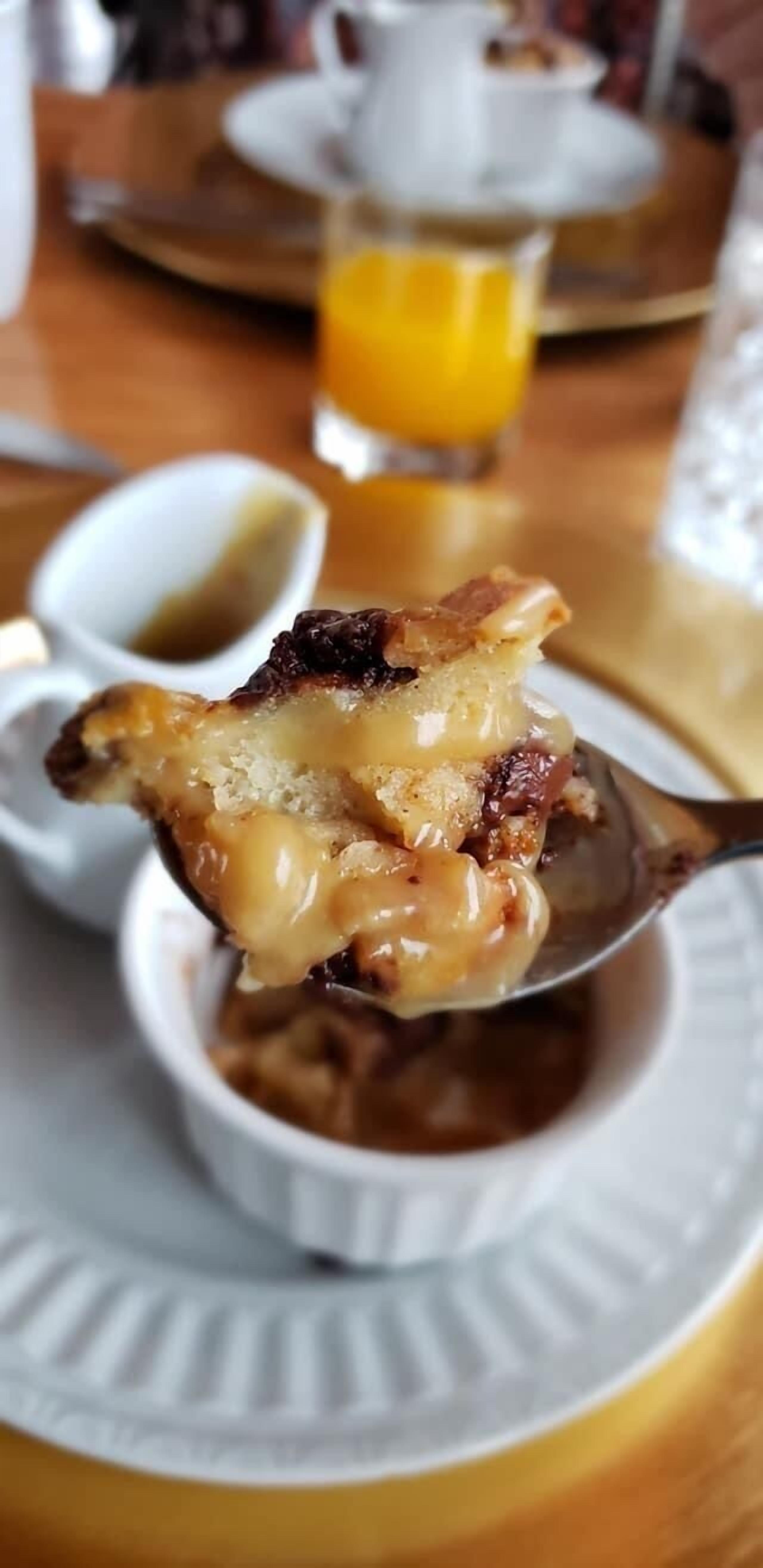 Eine Portion Essen mit cremiger Soße, ein Glas Orangensaft und eine kleine Schale Soße auf einem weißen Teller.