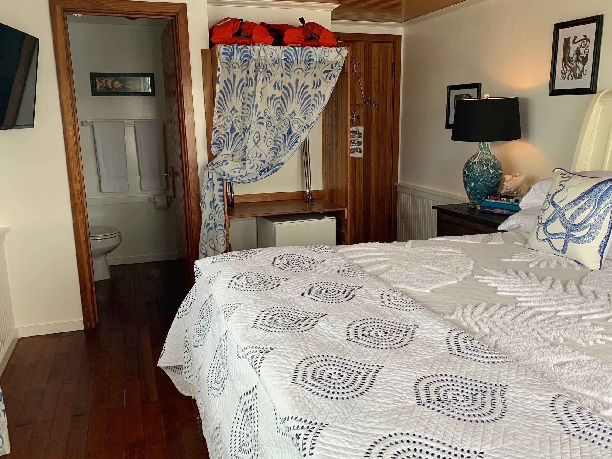 A bedroom with a bed, a nightstand, a lamp, and a window with a curtain.