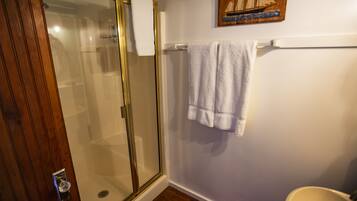 Une salle de bain avec une douche à parois de verre, un lavabo blanc et une porte en bois.