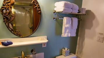 Un baño con lavamanos pedestal, inodoro, toallero y espejo con marco ornamentado.