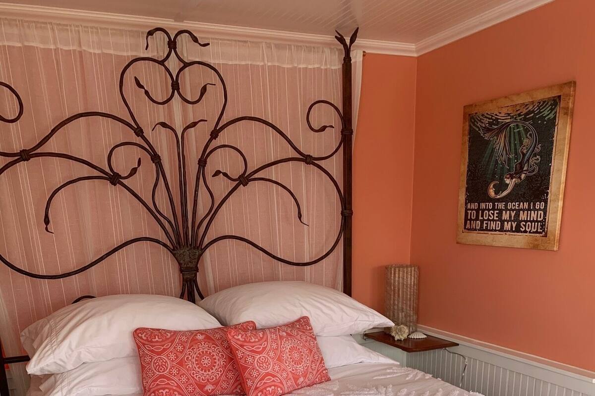 Ein Bett mit einem dekorativen Kopfteil, zwei gemusterten Kissen und einer strukturierten Tagesdecke.