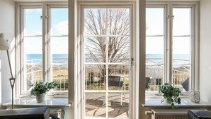 A room with a large window overlooking a deck and a view of trees and a body of water. There are two potted plants on the windowsill. - Awesome home in Brantevik with sauna (Brantevik)