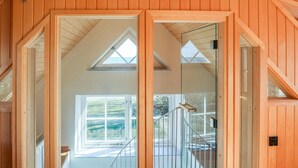 A wooden interior with a glass door leading to a balcony with a view of greenery. - Awesome home in Brantevik with sauna (Brantevik)