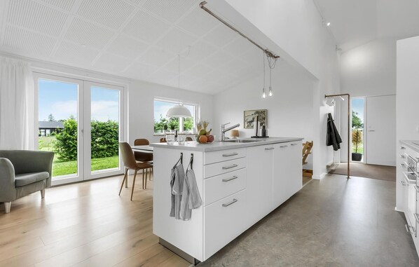 A modern kitchen with a large island, a dining area with a view of greenery, and a casual seating area with a sofa. - Amazing home in Odder with kitchen (Odder)